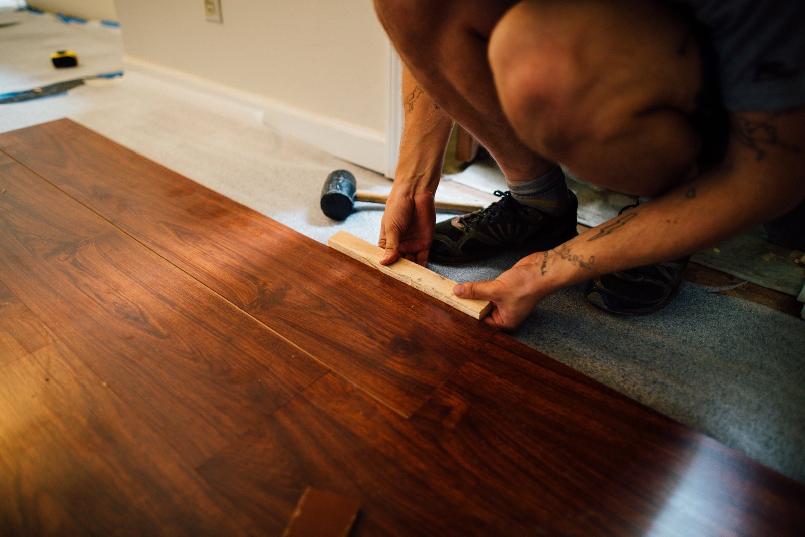Hands installing a hardwood floor plank