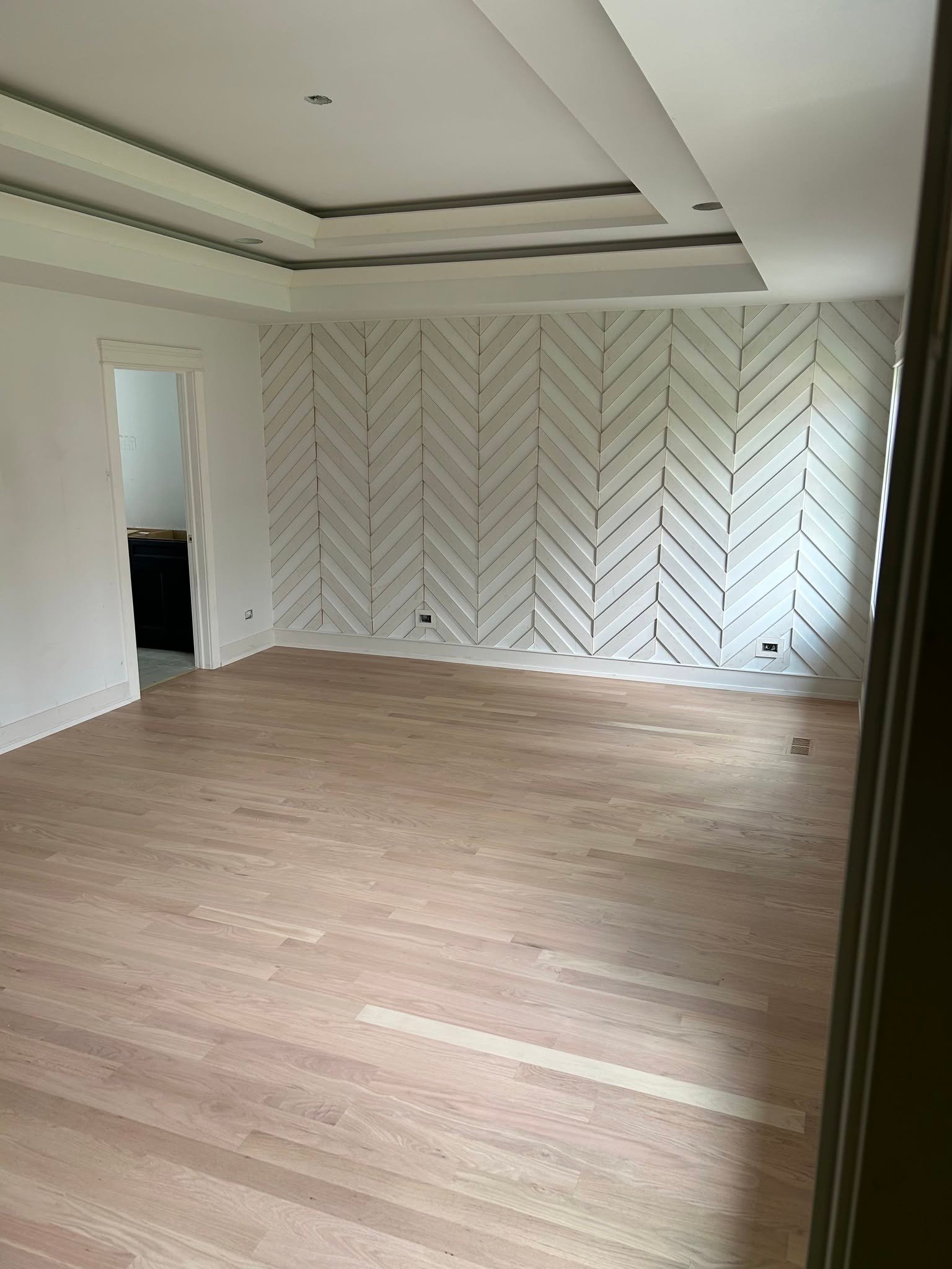 Herringbone pattern hardwood flooring with matching accent wall
